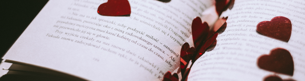 Imagem de um livro de poesias aberto com vários corações vermelhos de papel em seu interior
