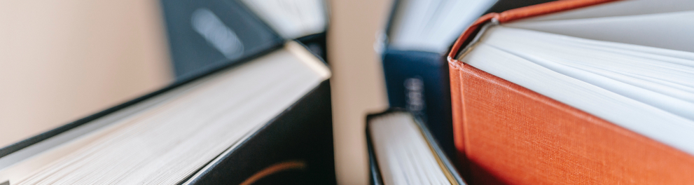 Cinco livros estão na posição vertical e com suas quinas próximas, quase se encostando todos