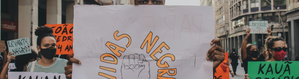Jovens negros em uma rua brasileira com cartazes de protestos contra a discriminação racial