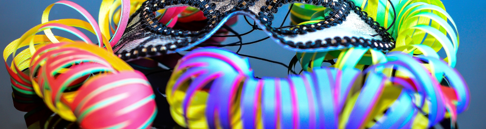 Imagem de uma máscara de carnaval bem colorida e cheia de lantejoulas nas cores amarela, rosa, azul e roxa
