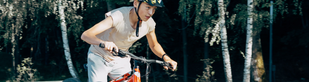 Uma pessoa está em uma bicicleta vermelha e usando capacete de segurança