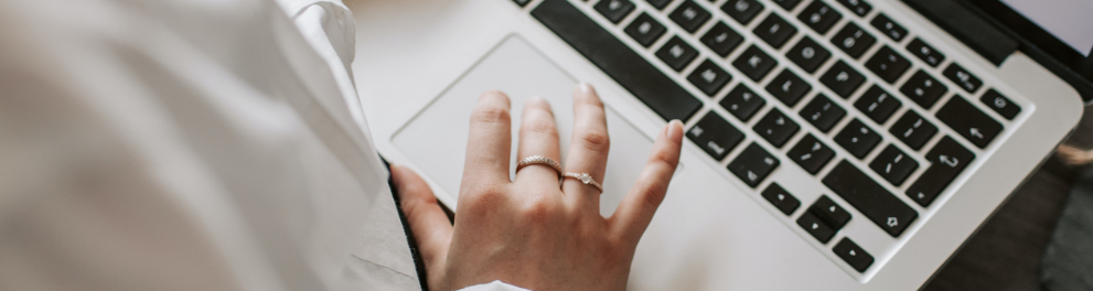 Um notebook aberto e sendo teclado por mãos femininas