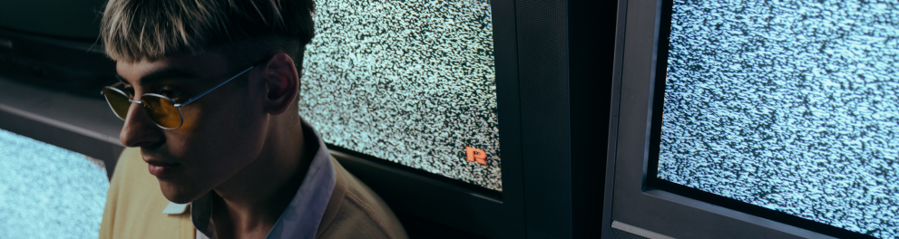 Imagem mostra um garoto diante de aparelhos de TV