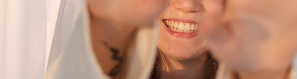 Uma mulher loira e branca está com os dois braços esticados à frente mostrando as palmas da mão para quem bateu a foto. Ela está sorridente e demonstrando imensa felicidade