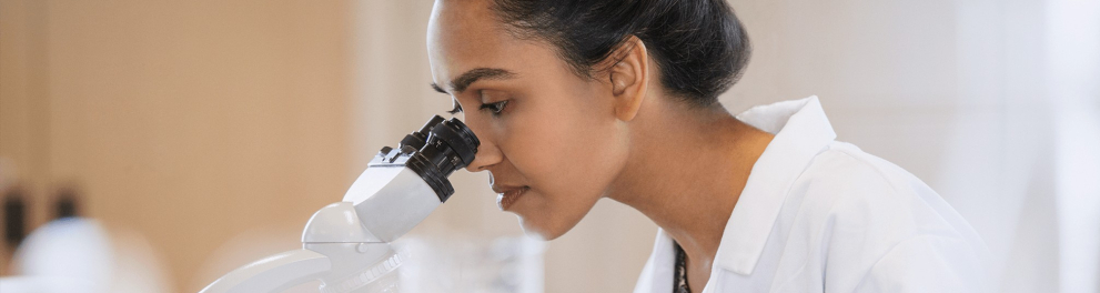 A imagem mostra uma mulher usando um microscópio