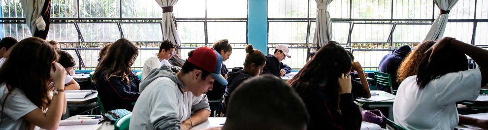 Uma sala de aula com alunos sentados e concentrados em seus livros