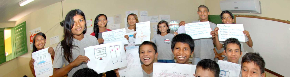 Alunos em uma sala de aula segurando plaquinhas feitas com papel A4