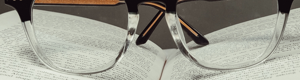 Close em um livro aberto com um óculos de grau em cima dele