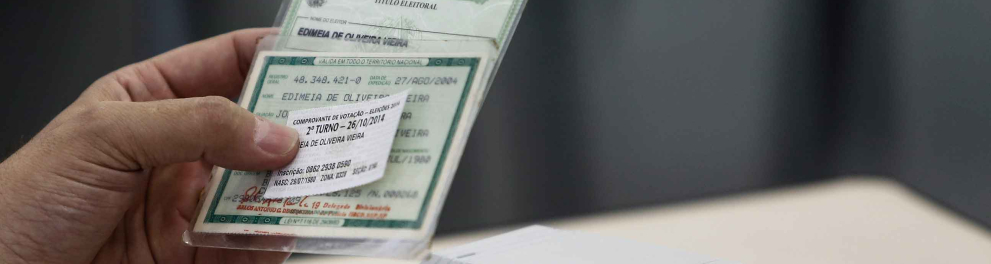 Um mesário conferindo os dados de uma pessoa em um dia de votação