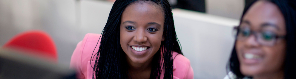 Duas mulheres negras sorrindo e olhando para um computador