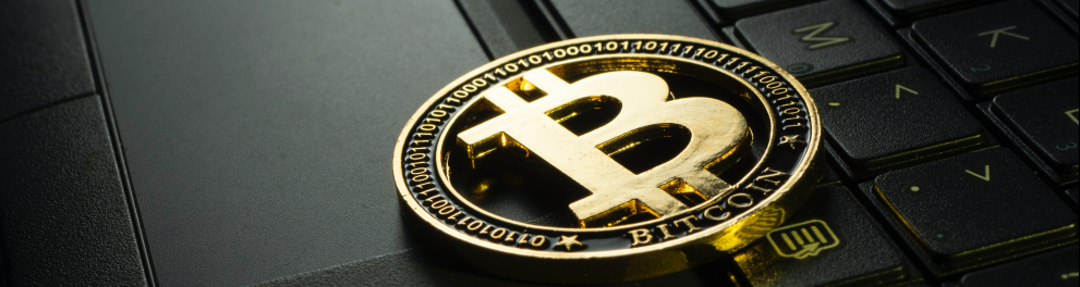 A imagem mostra uma criptomoeda em cima de um notebook