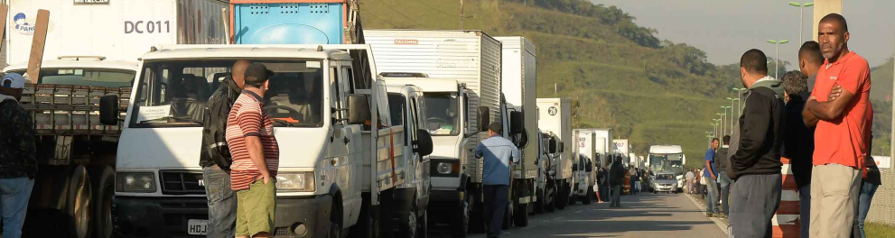 A imagem mostra uma via com caminhões parados em meio à greve dos caminhoneiros