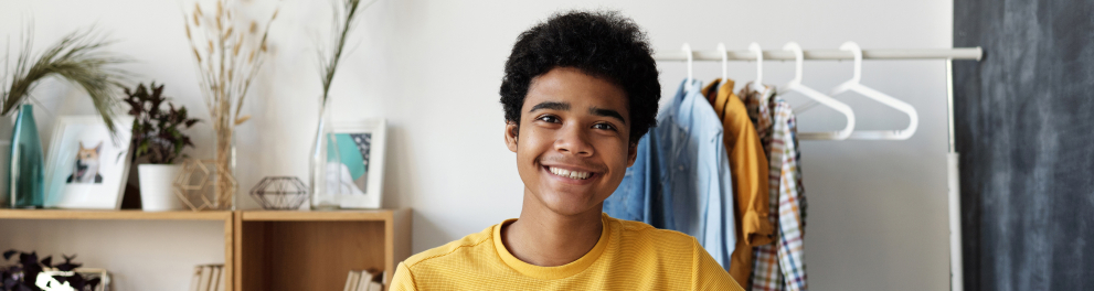 A imagem mostra um adolescente segurando um tablet e sorrindo para a foto