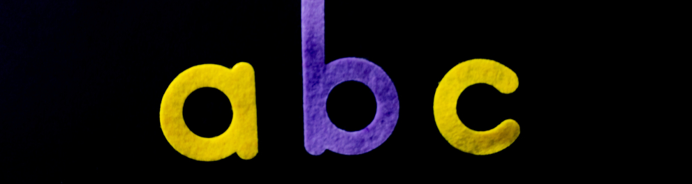 As letras "a", "b" e "c" uma do lado da outra sobre um fundo preto. 