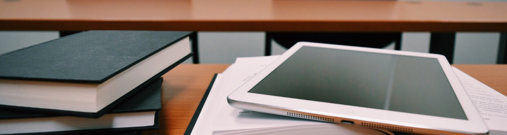 Uma mesa de estudo em uma sala de aula com cadernos, livros e um tablet
