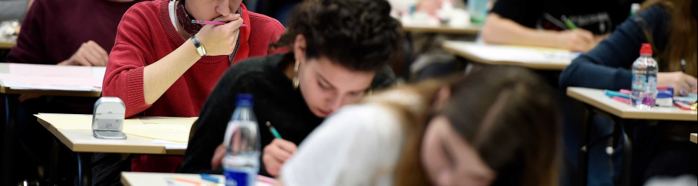 Uma sala de aula com diversos estudantes fazendo prova