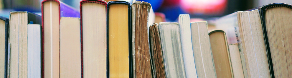 Vários livros estão lado a lado em uma prateleira