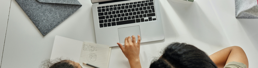 Imagem mostra uma mulher e uma garota em frente a um notebook