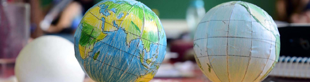 Dois pequenos globos mundiais feitos de papel estão em cima de copinhos de plástico, que serviram de base para as esferas