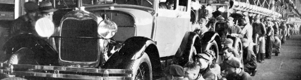 Imagem em preto e branco de uma antiga indústria da Ford, com seus funcionários fabricando os carros