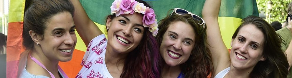 Um grupo de mulheres segurando uma bandeira LGBTQIA+