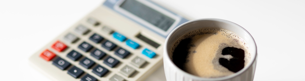 Uma calculadora ao lado de uma xícara de café