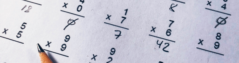 Zoom em uma folha branca com várias contas matemáticas e um lápis em cima da folha