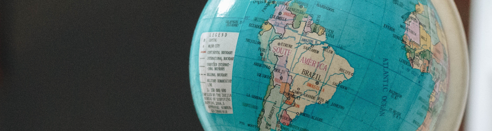 Um globo azul mostrando o mapa mundi, porém com a América do Sul virada para quem bateu a foto