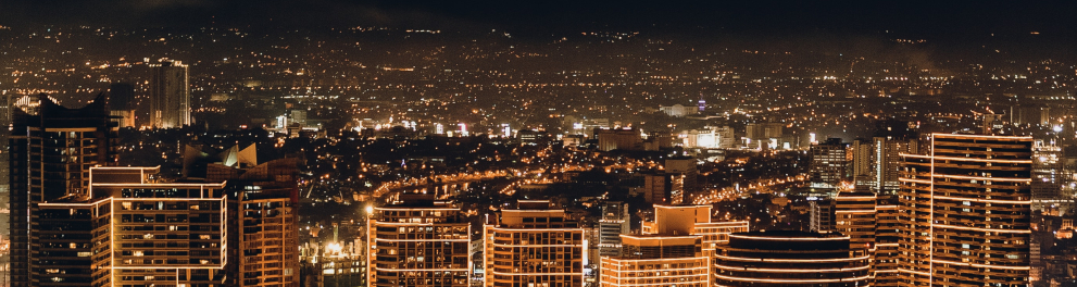 Imagem de aérea e distante de uma cidade toda iluminada durante uma noite