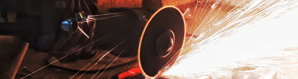 Uma serra está cortando uma parte de um metal cilíndrico em uma fábrica