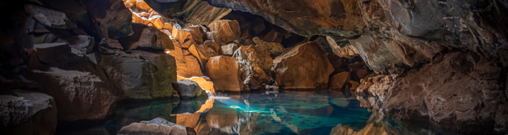 Imagem de uma gruta, com um aquífero cristalino e várias rochas ao redor