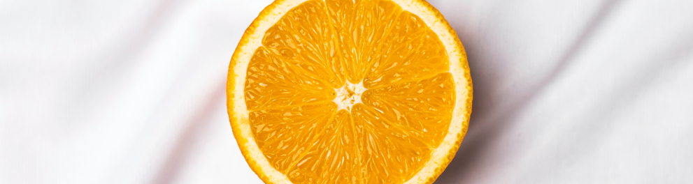 A metade de uma laranja foi cortada e está em cima de um tecido branco