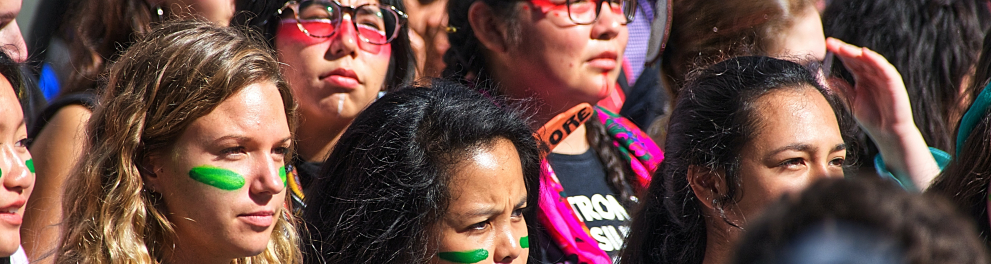 Várias mulheres reunidas na rua com os rostos pintados semelhantes às pinturas do povo indígena