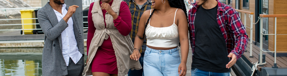 Cinco pessoas jovens e estão caminhando sorridentes e interagindo entre si em direção a quem bateu a foto