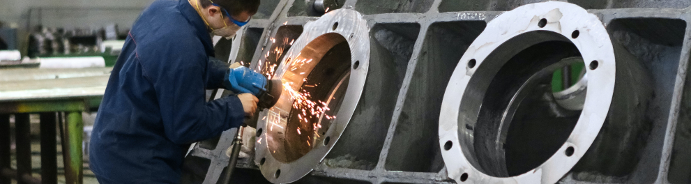 Um homem trabalhando soldando uma estrutura de ferro em uma metalúrgica