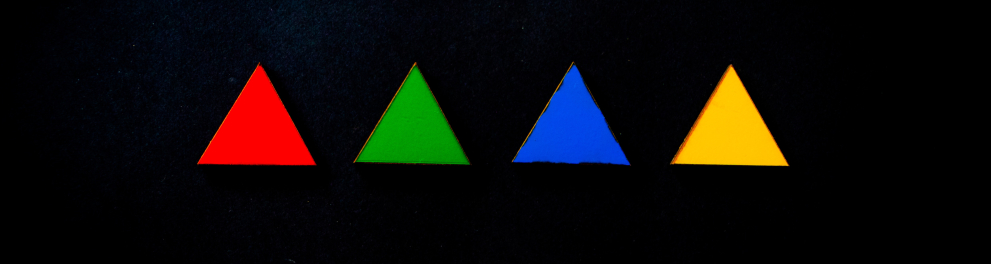 Quatro triângulos lado a lado sobre um fundo preto. Os triângulos são vermelho, verde, azul e amarelo respectivamente e possuem mesmo tamanho