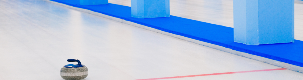 Uma pedra do esporte curling está sobre uma pista de gelo com uma linha vermelha traçada