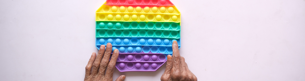 As mãos de uma pessoa idosa estão tocando um objeto octogonal colorido