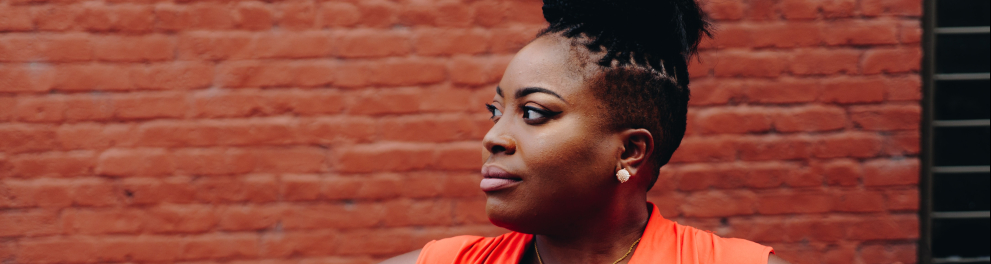 Uma mulher negra com as mãos na cintura e olhando para o seu lado direito