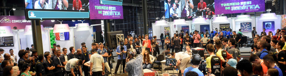 Imagem de um festival de robótica, com várias pessoas na imagem e muita iluminação