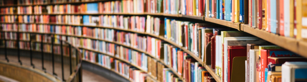 Corredor de uma biblioteca mostrando inúmeras obras guardadas em estantes 