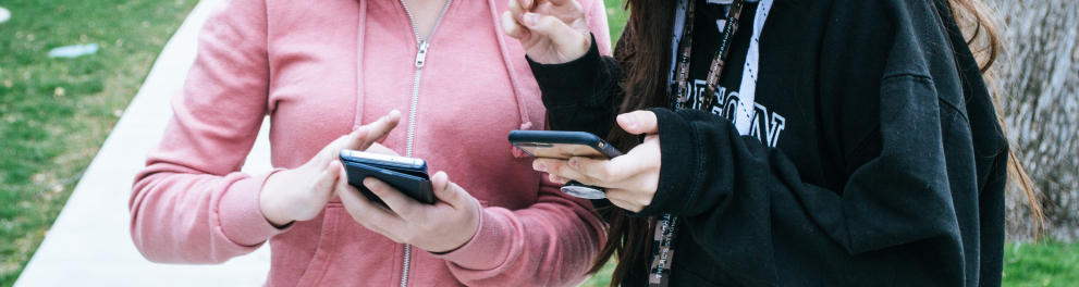 Duas mulheres seguram, cada uma, um celular.