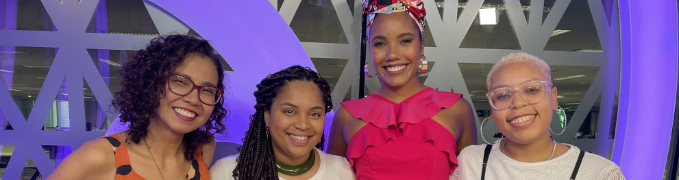 Quatro mulheres estão de pé e sorrindo.