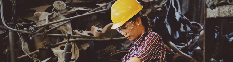 Uma mulher com um capacete amarelo operando uma máquina industrial