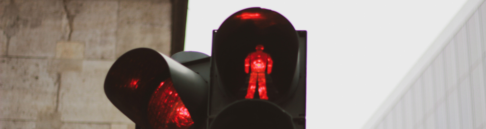 Um semáforo com as luzes vermelhas para passagem de carros e travessia de pedestres