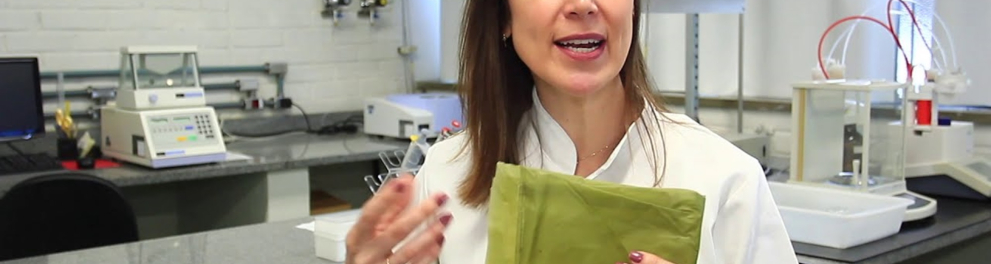 Uma cientista branca está segurando um envelope verde e falando com quem fez a foto