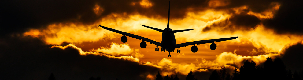 Imagem da silhueta de um avião decolando e de costas para quem fez a foto, que ainda mostra um lindo tom de amarelo no céu