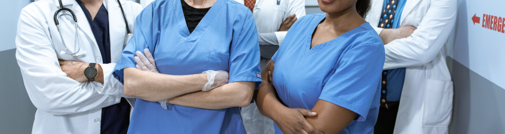 Médicos e enfermeiros estão lado a lado trajando seus jalecos e uniformes da profissão posando para a quem bateu a foto