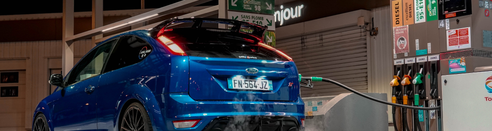Um carro azul está em um posto de gasolina abastecendo com gasolina ou etanol