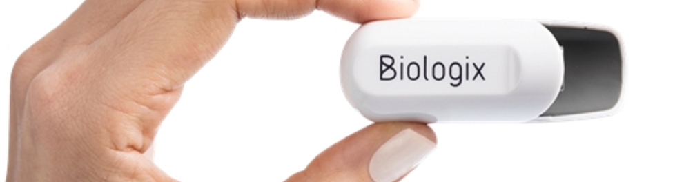 Mão esquerda de uma pessoa branca segurando um objeto do tamanho e formato de um pen drive, na cor branca, e com a palavra "Biologix" escrita
